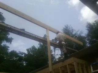 Carpenter setting a ridge beam over a new addition frame — Ice Dam Removal by Roofing Brothers in Bly