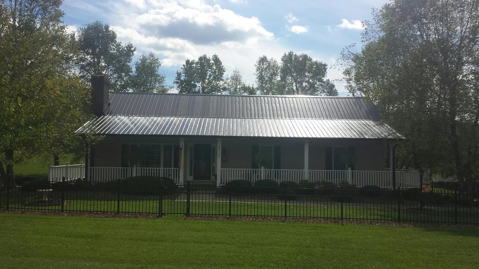 Gray metal roof on a brick ranch with a full width front porch — Gutter Guard Installation work by our crew in Bly