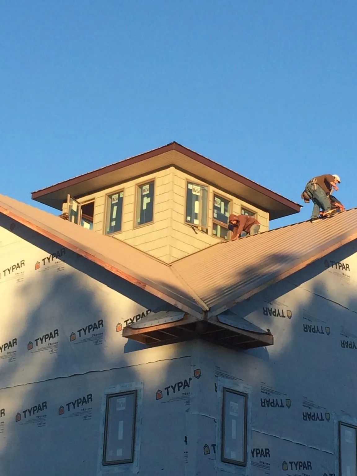 Roofers working around a rooftop cupola on a new metal roof at sunset — Roof Waterproofing in Bly by Roofing Brothers